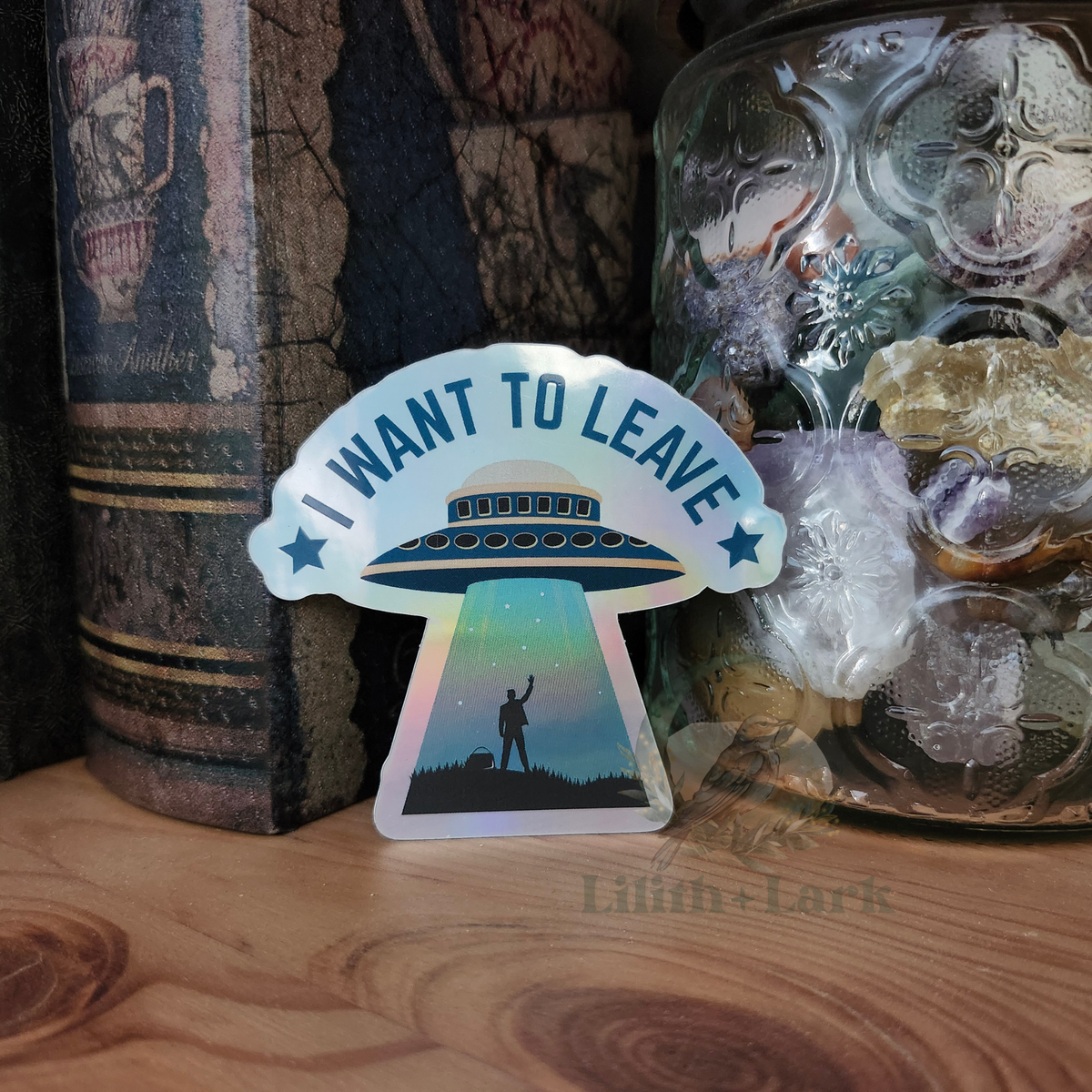 Holographic sticker with 'I Want to Leave' words, featuring an image of an UFO beaming up a human.